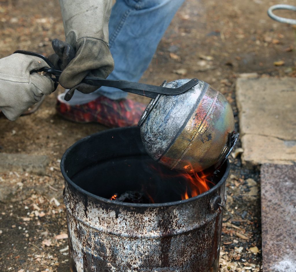 A potter lifting a fired vessel from an open kiln