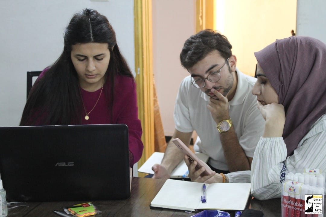 Three colleagues working together around a laptop