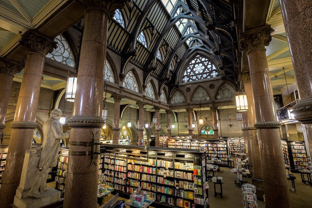 The interior of a grand library, with tall bookshelves under a vaulted roof